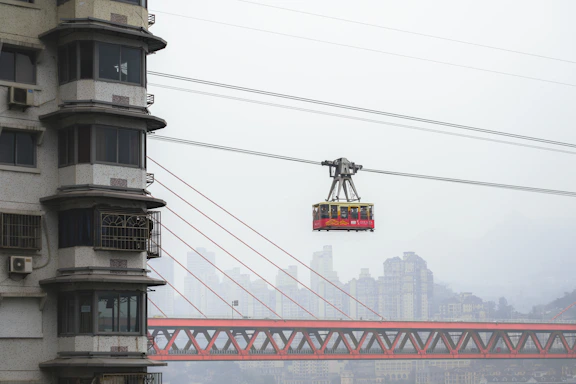 a cable car going over a bridge with a city in the background