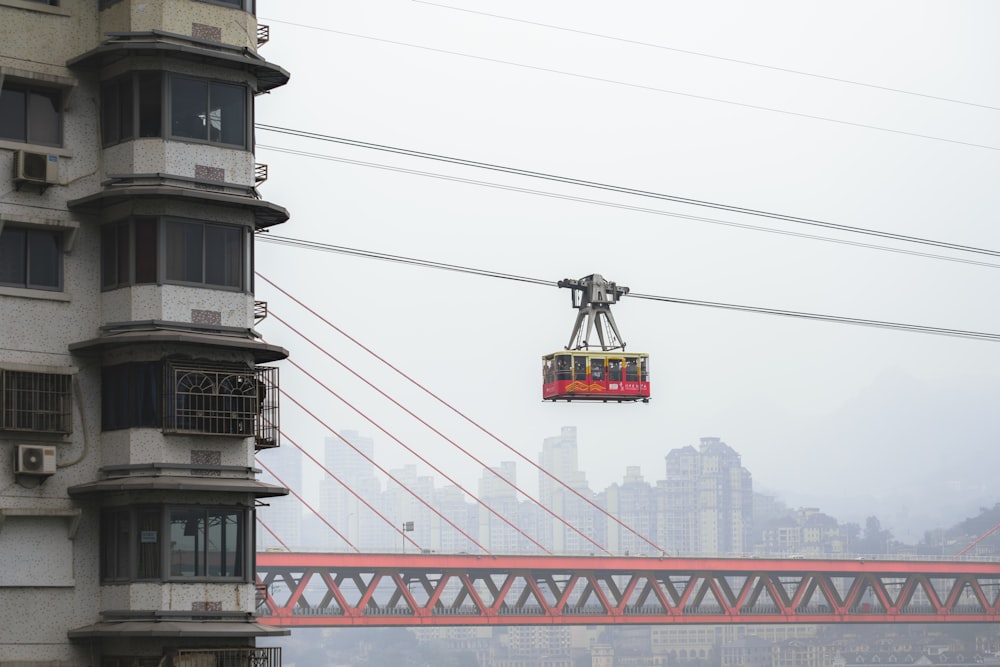 a cable car going over a bridge with a city in the background