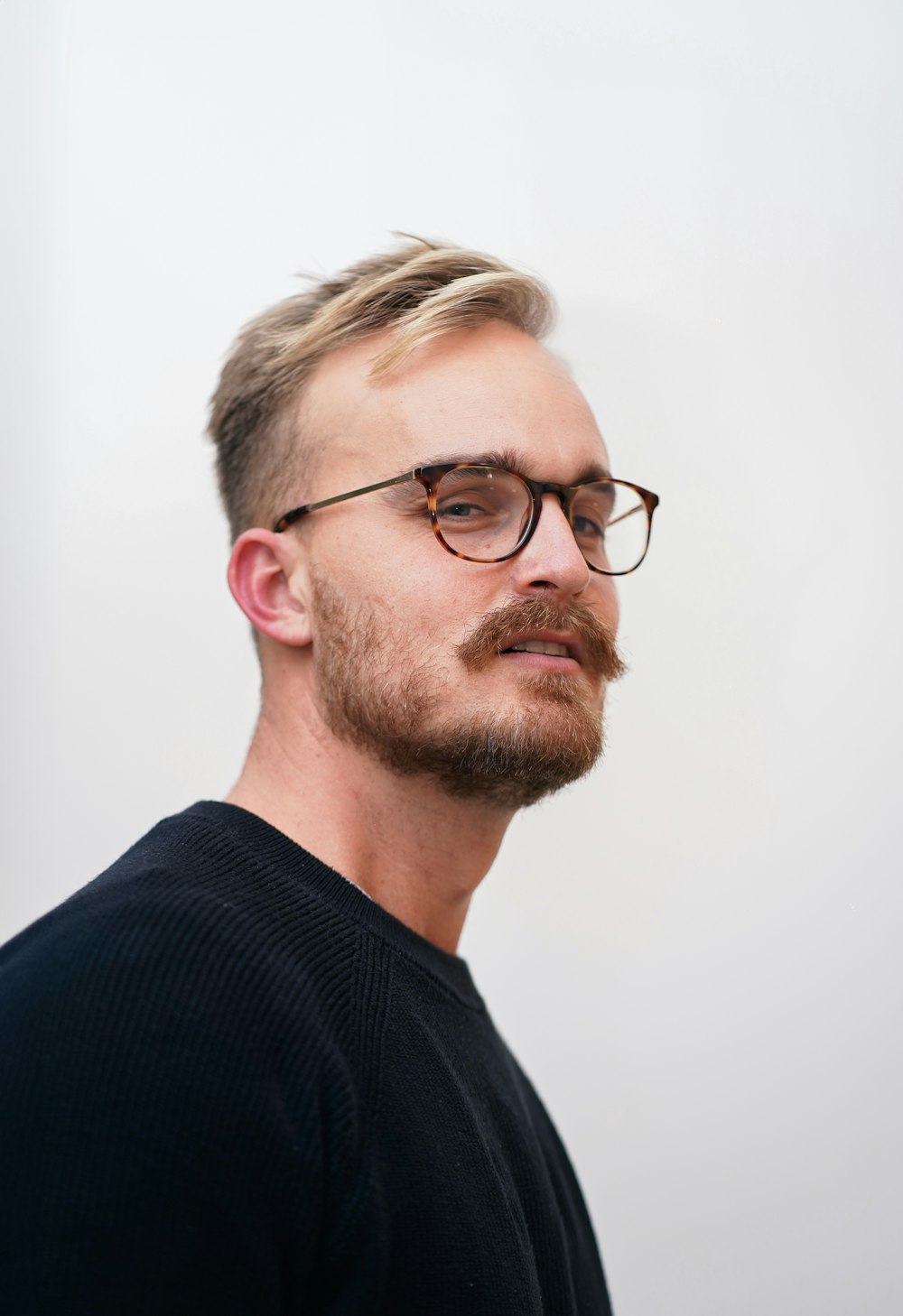 a man with a goatee and glasses looking off to the side