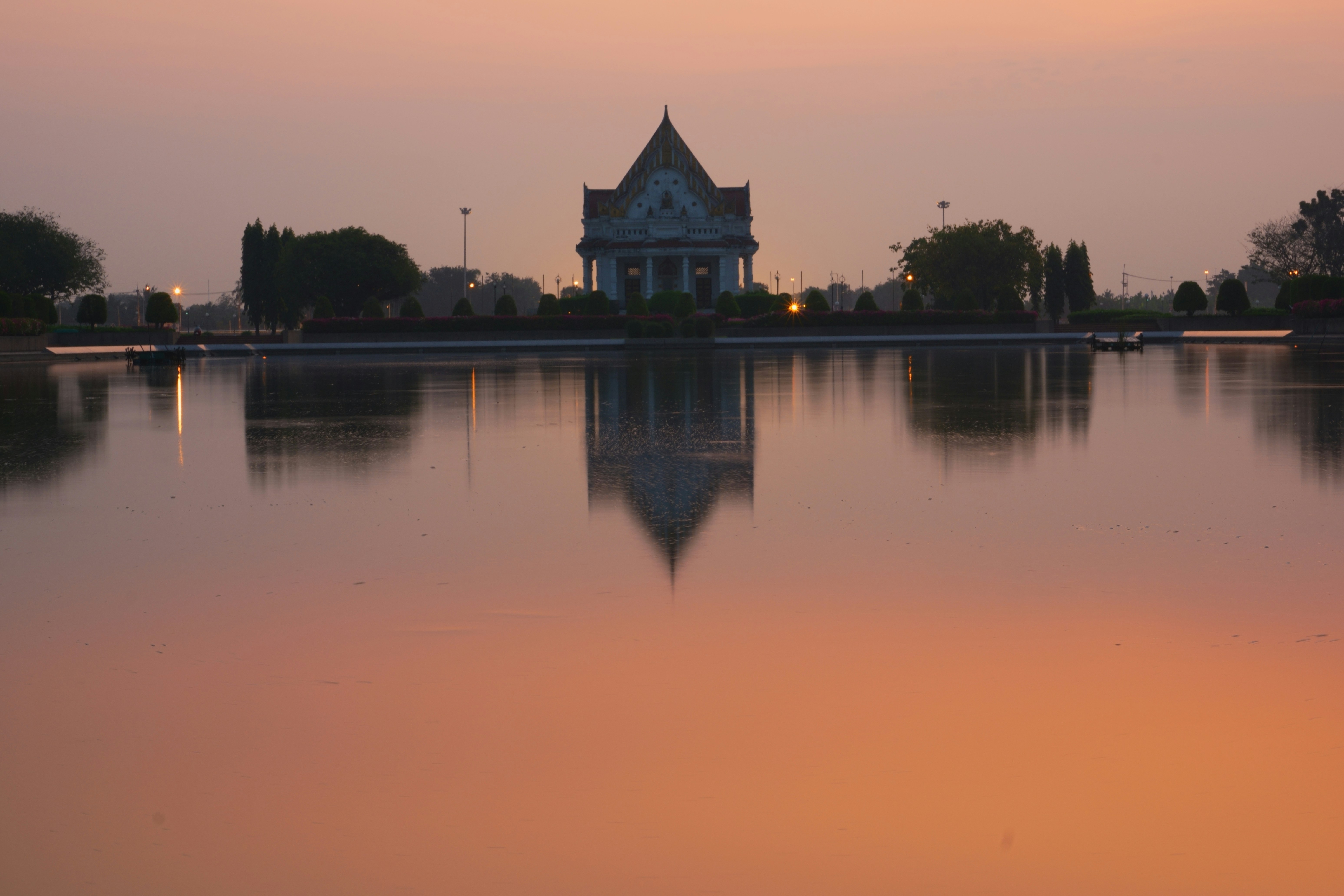 Sacred lake at sunrise with temple ghats, oil lamps floating on calm reflective water