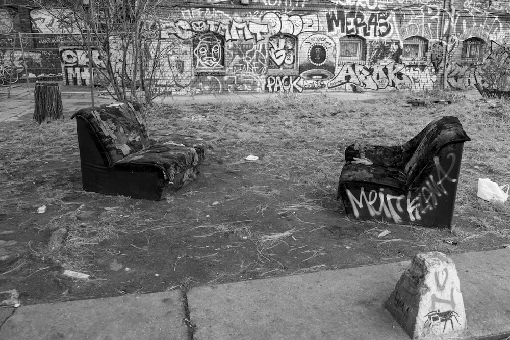 Una foto en blanco y negro de dos sofás frente a una pared cubierta de grafitis