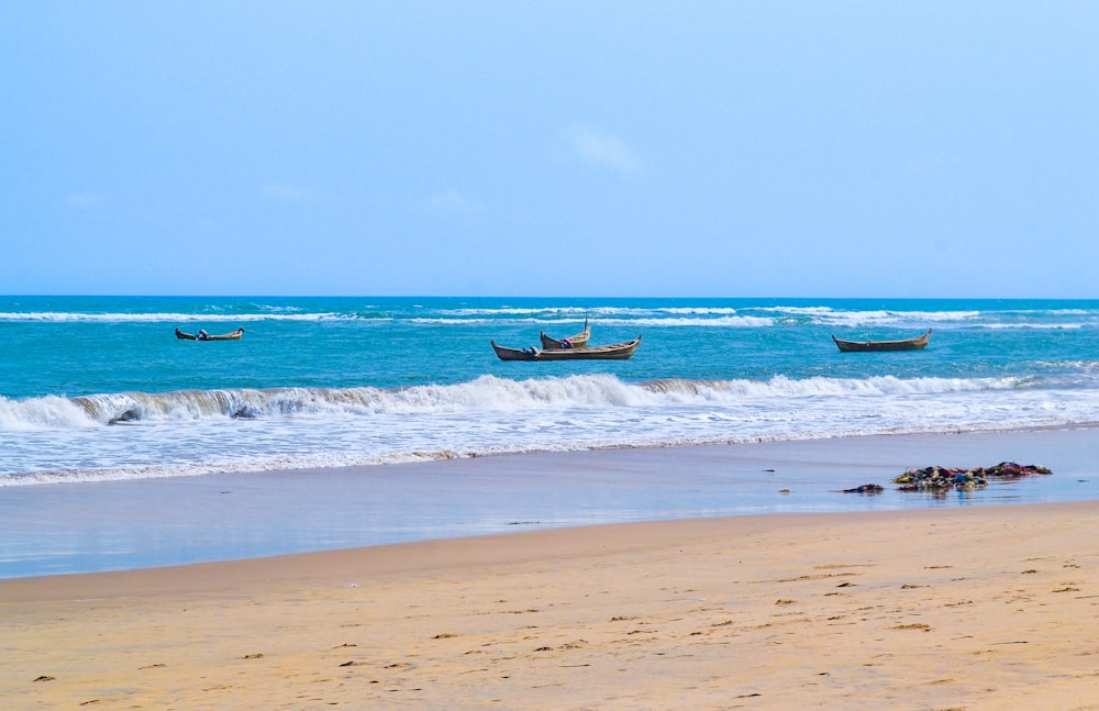 a group of boats floating on top of a sandy beach