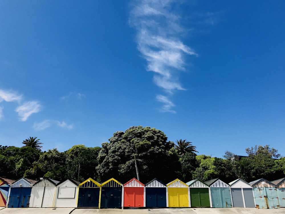 a row of brightly colored beach huts under a blue sky