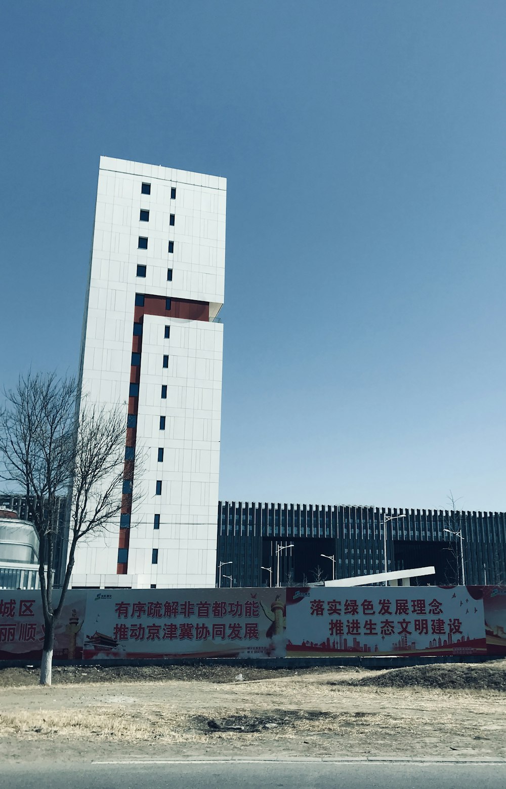 a tall white building with a red and white stripe on it