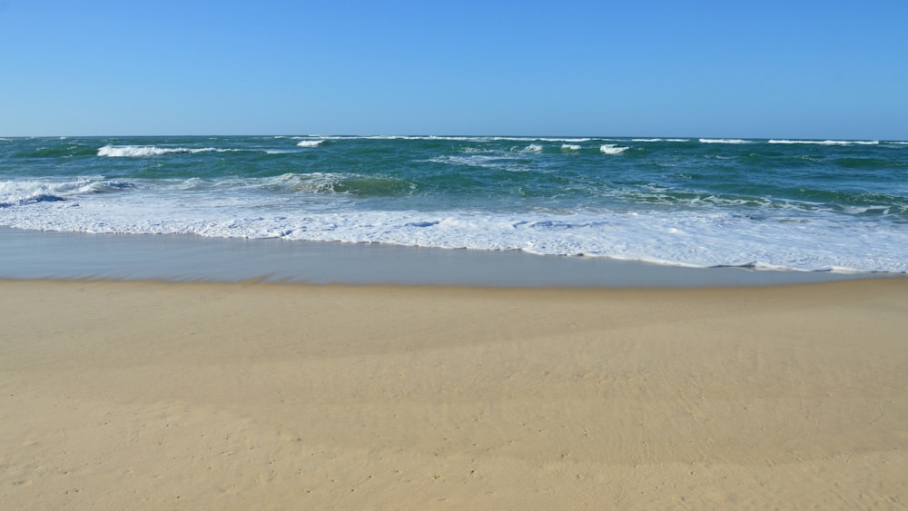 a sandy beach with waves coming in to shore