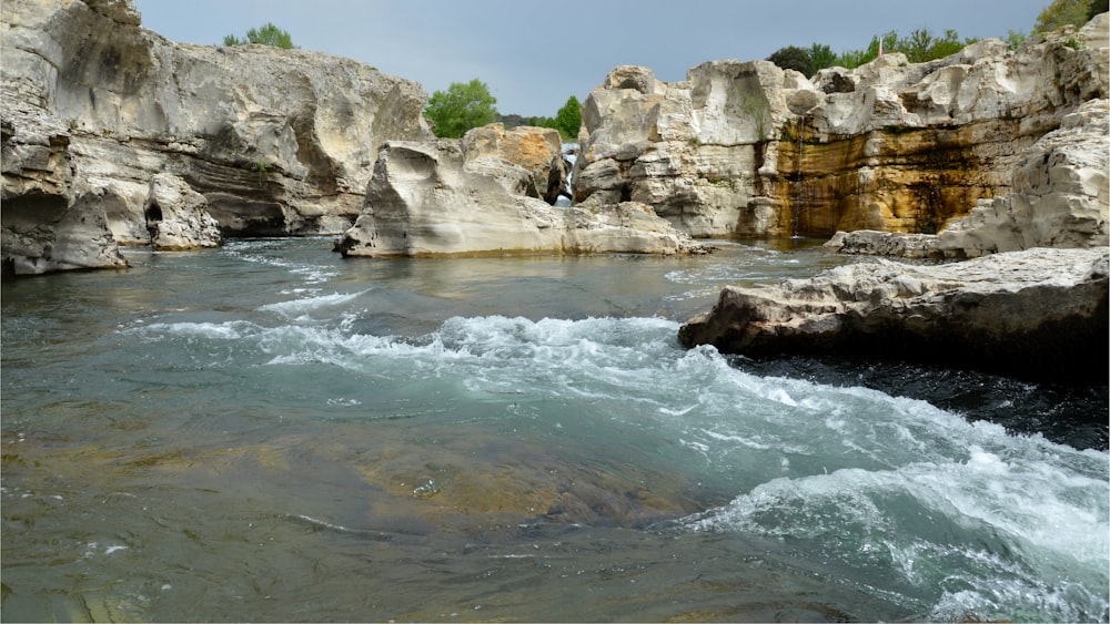 a river running through a rocky landscape next to a forest