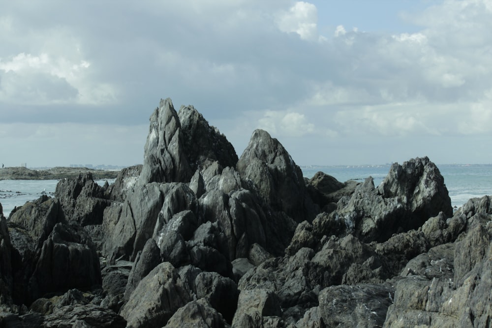 a rocky beach with a body of water in the background