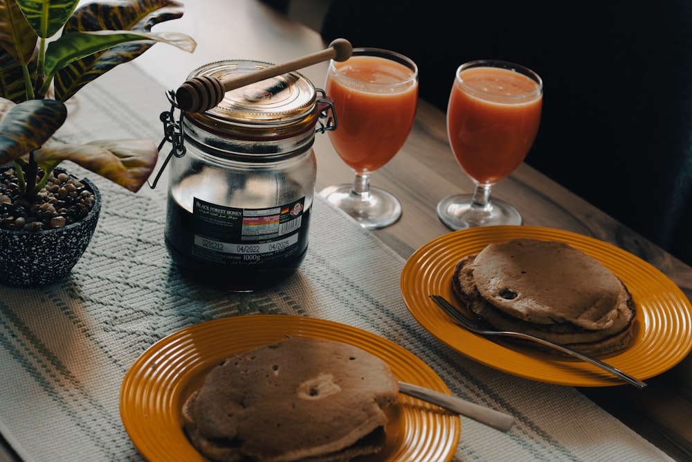 a table topped with two plates of pancakes and two glasses of juice