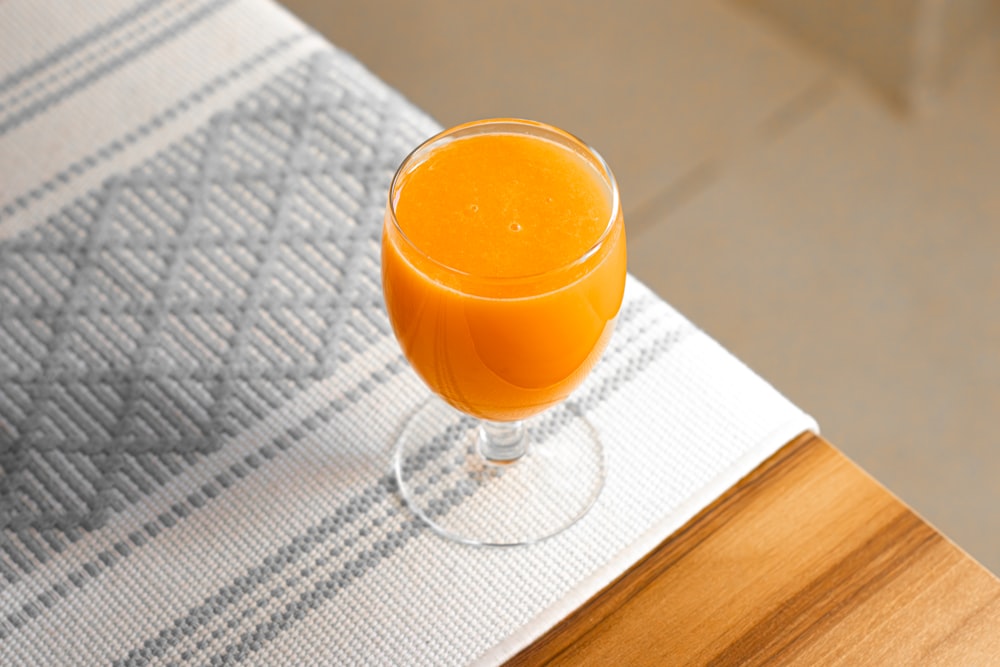 a glass of orange juice sitting on top of a table