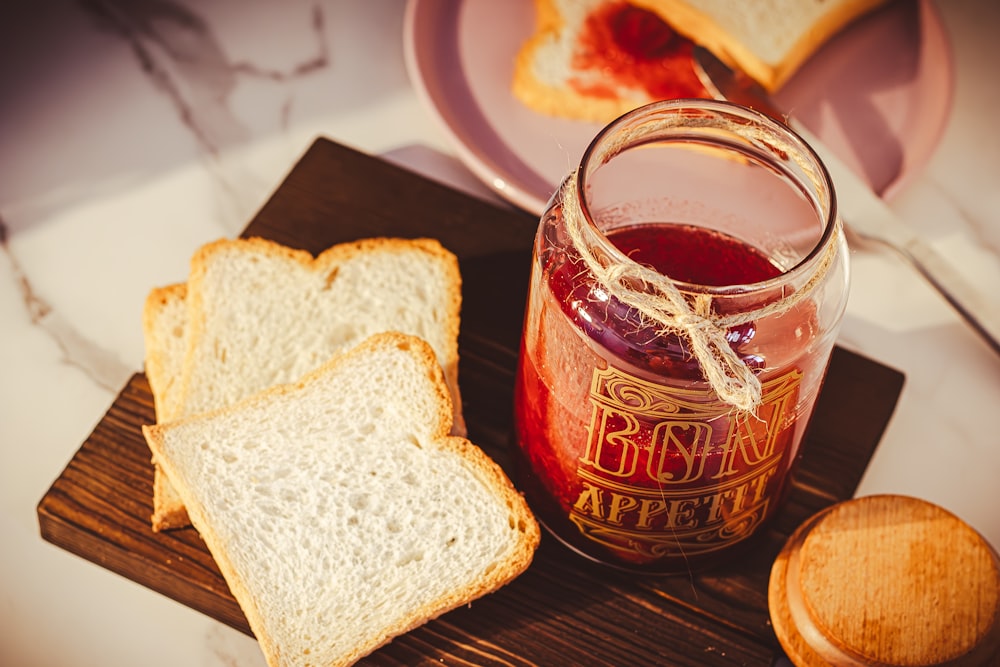 a jar of jelly next to slices of bread