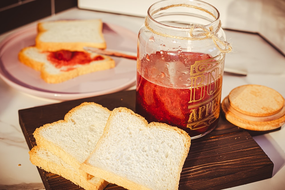 a jar of jelly and slices of bread on a cutting board