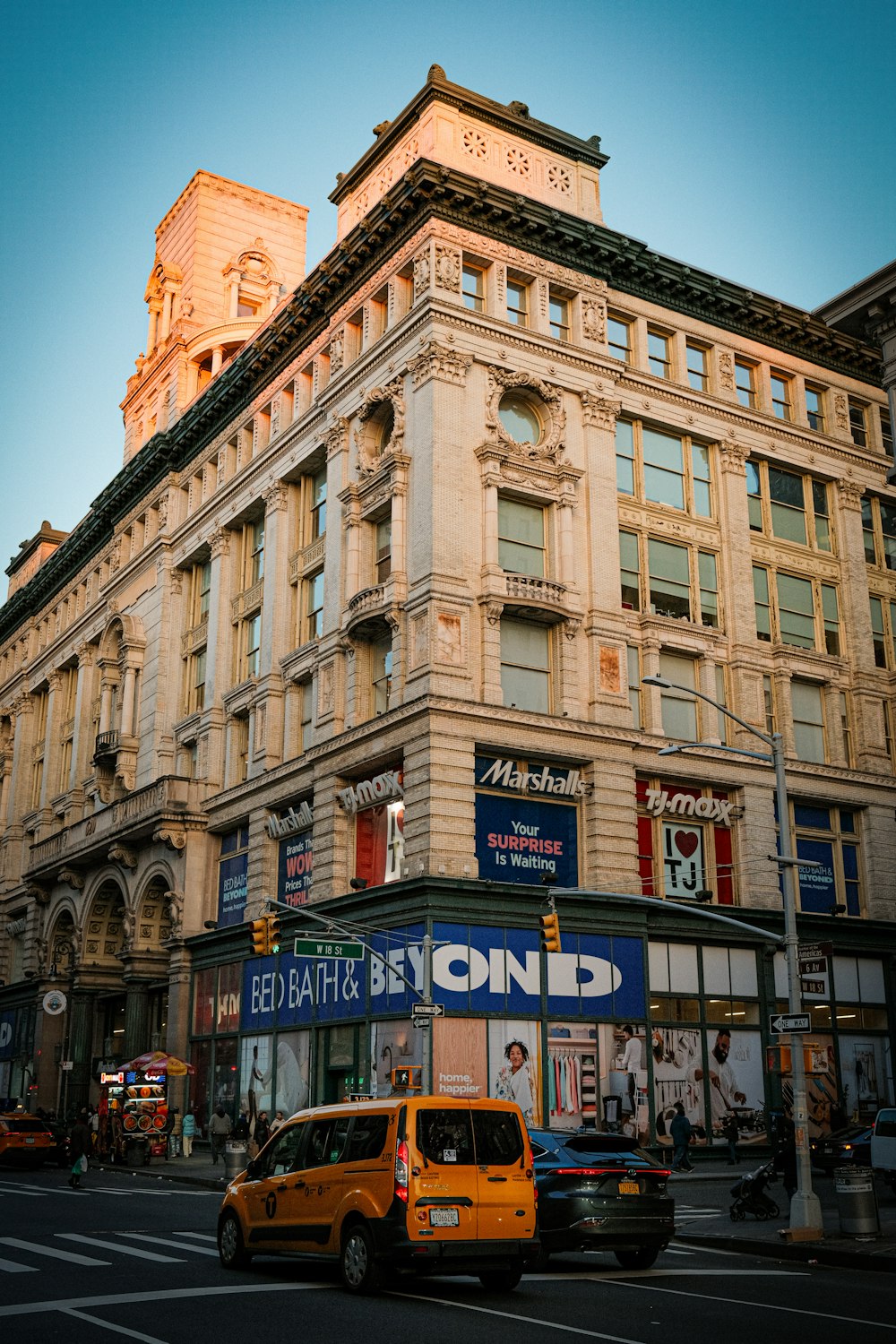 a yellow taxi driving down a street next to a tall building