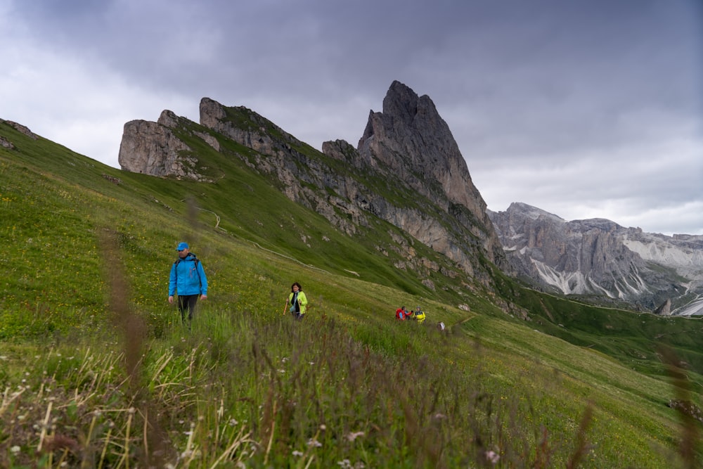 a group of people hiking up a grassy hill