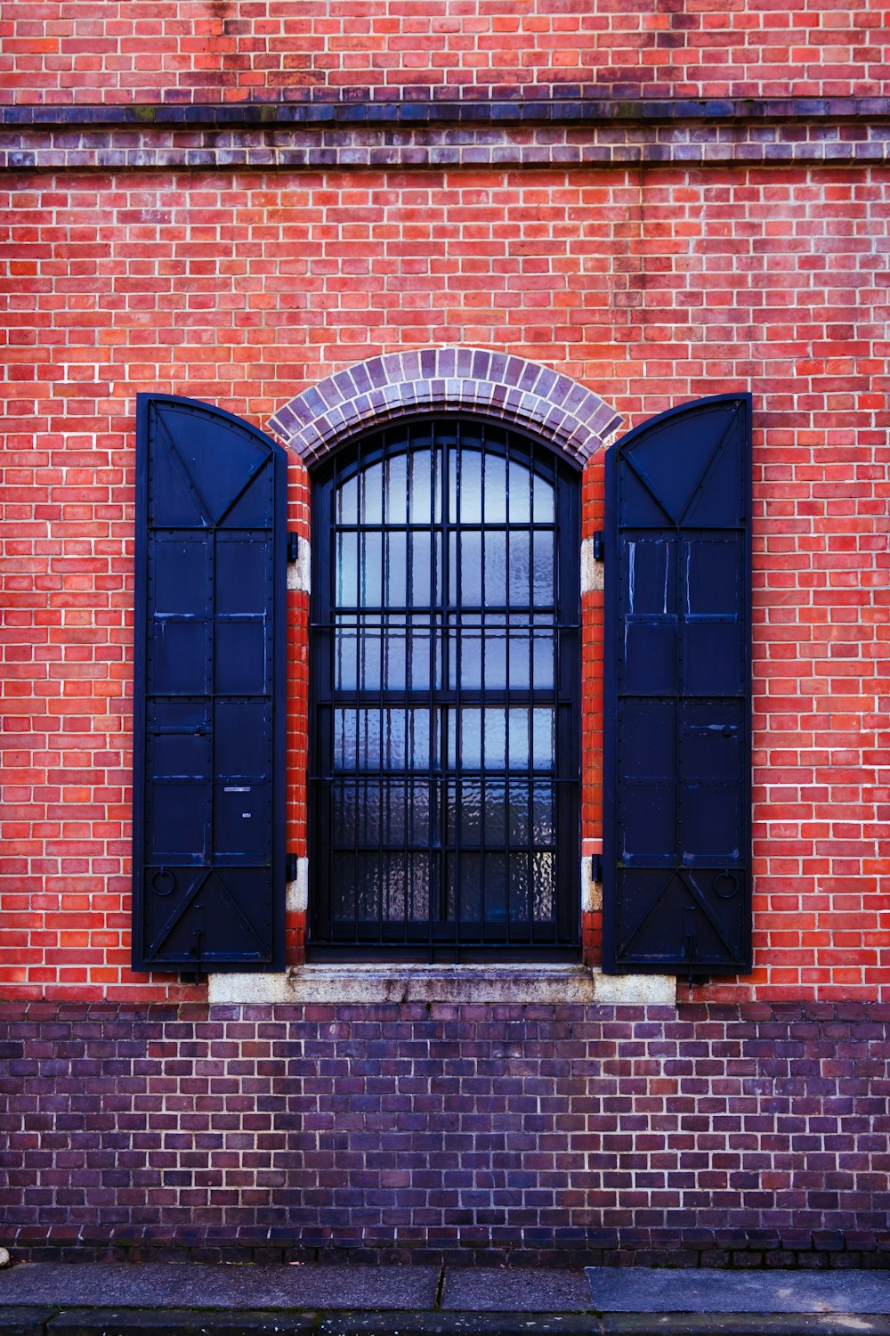 a red brick building with three black shutters