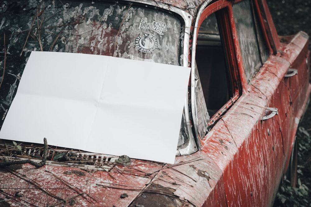 an old red car with a white sheet of paper on it