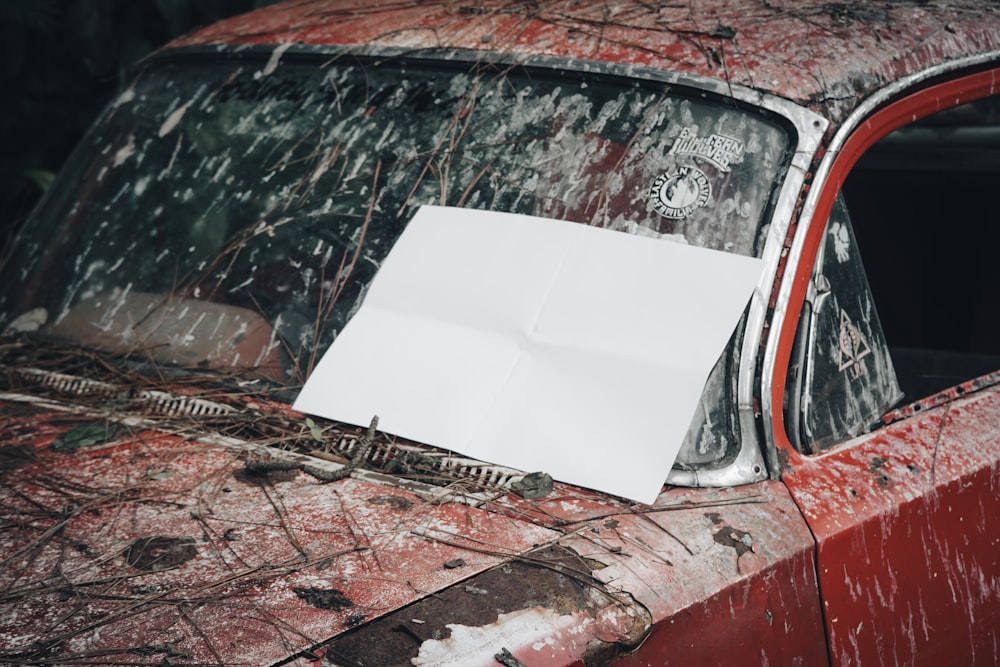 an old red car with a piece of paper stuck to the windshield
