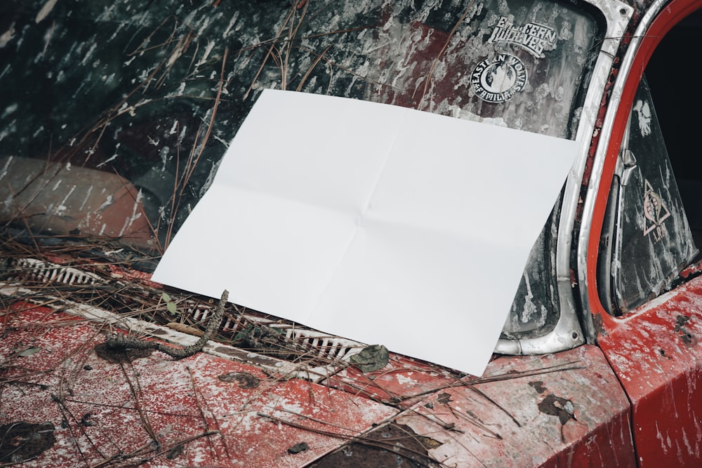 a white piece of paper sitting on top of a red car