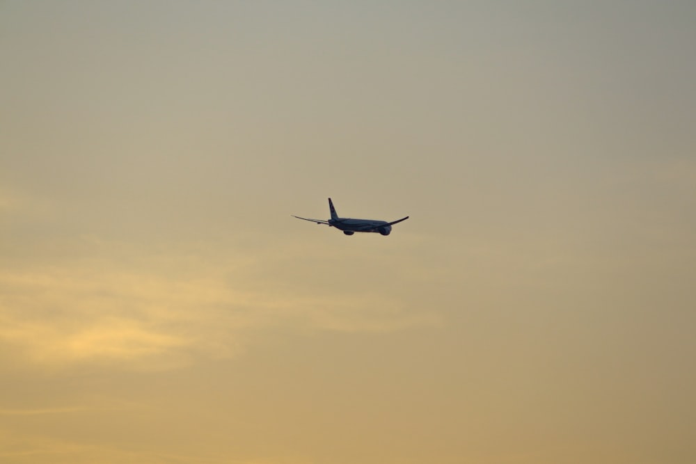 an airplane is flying in the sky at sunset