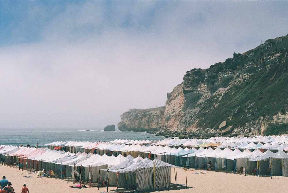 a beach filled with lots of white tents next to the ocean