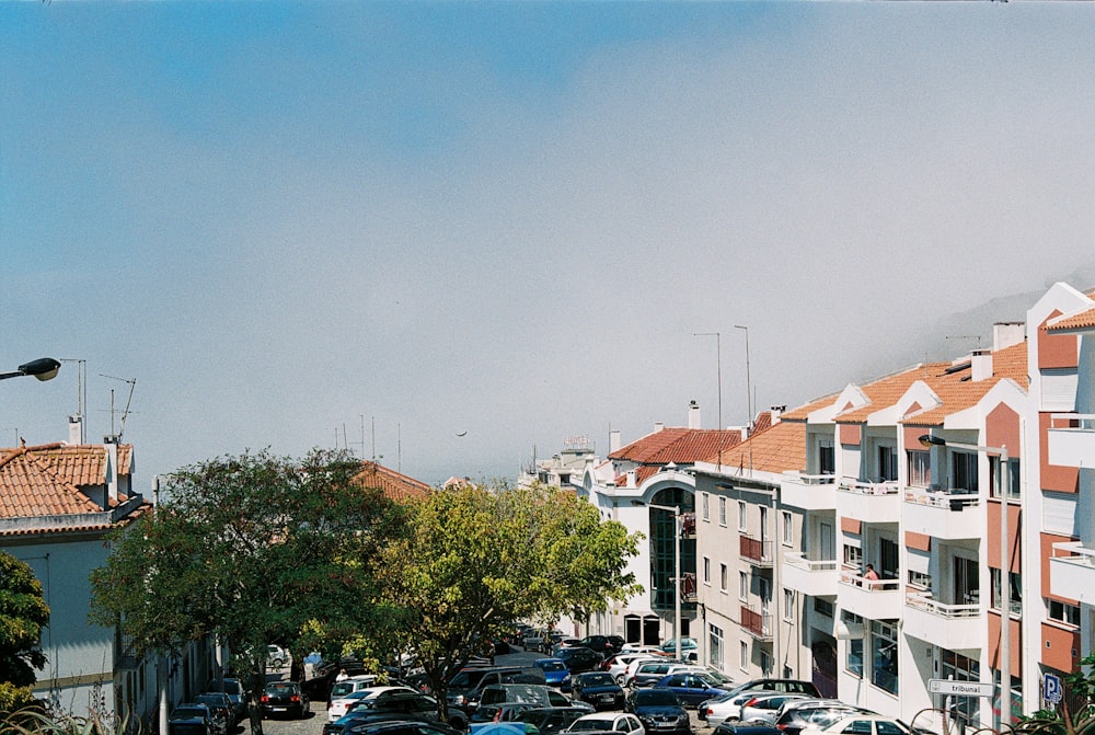 a street filled with lots of parked cars next to tall buildings