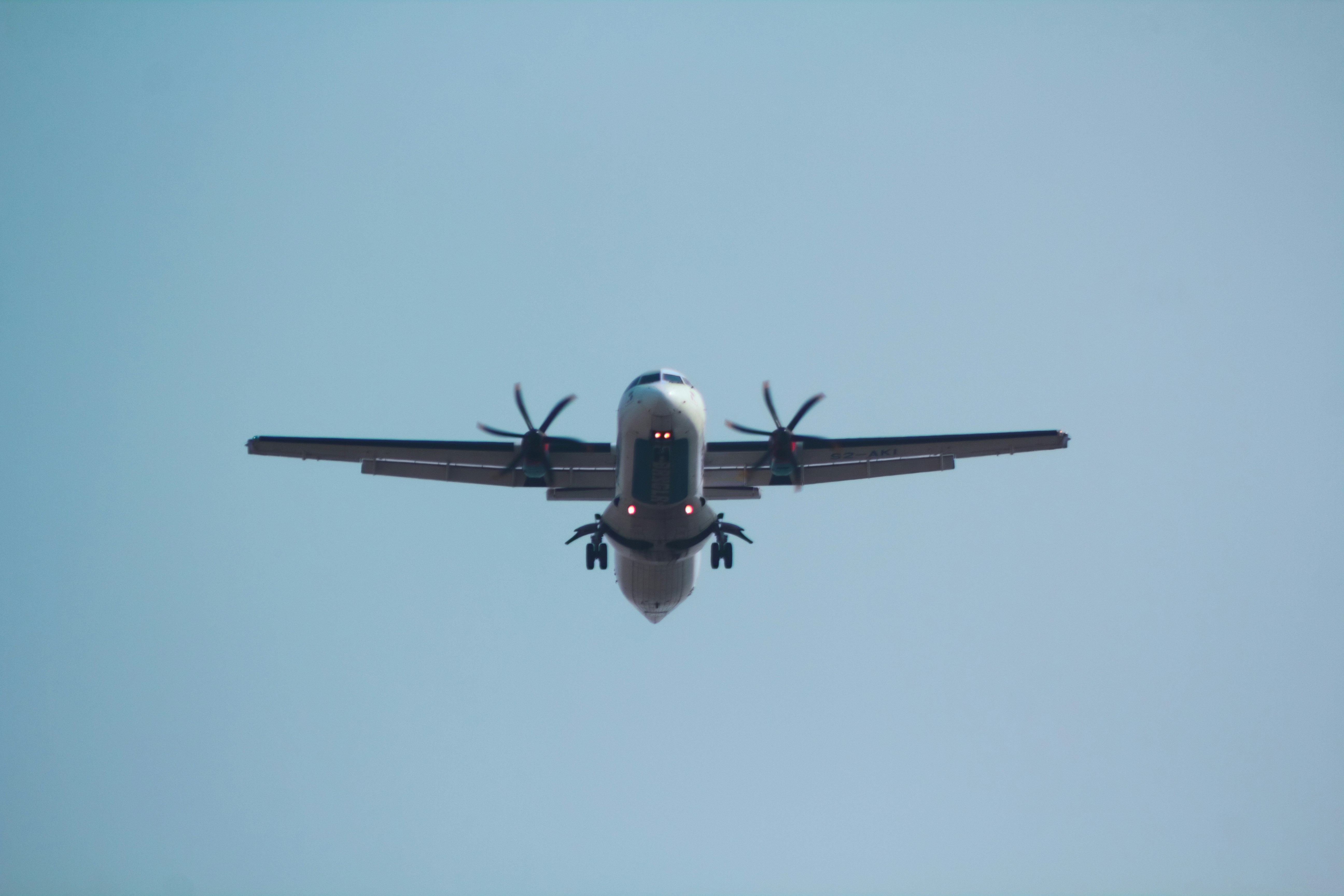 a large airplane flying through a blue sky, AT76 operated by US-Bangla Airlines.