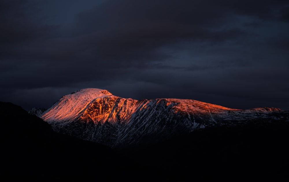 a snow covered mountain under a cloudy sky