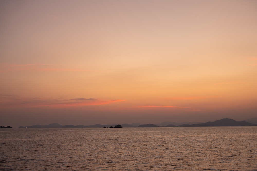 a large body of water with a sunset in the background