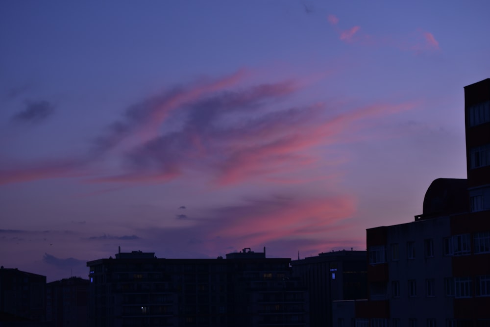 a pink and blue sky with some buildings in the background