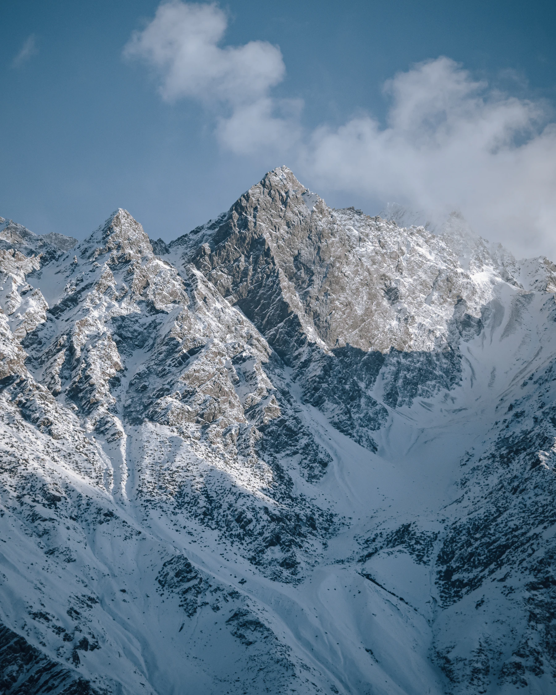 Snow-covered mountain range under clouds in Skardu