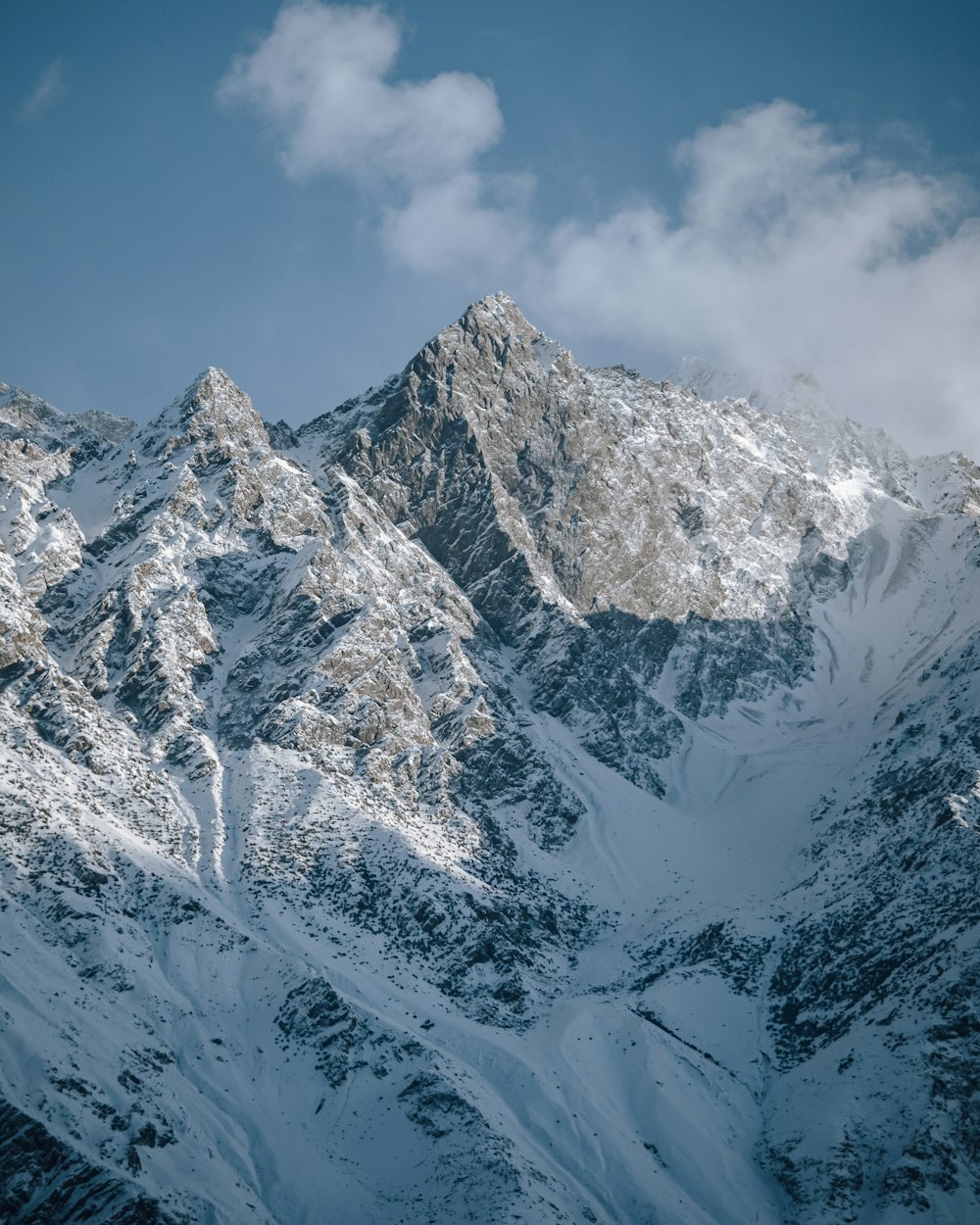 une chaîne de montagnes enneigée sous un ciel bleu nuageux