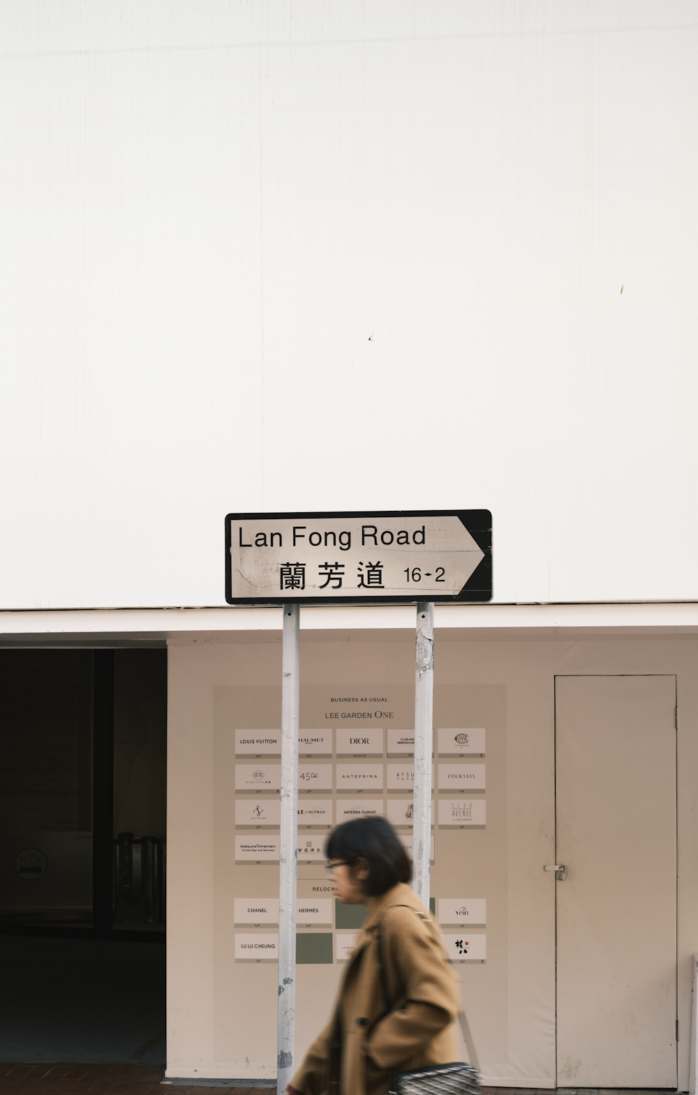 a woman walking down a street past a sign