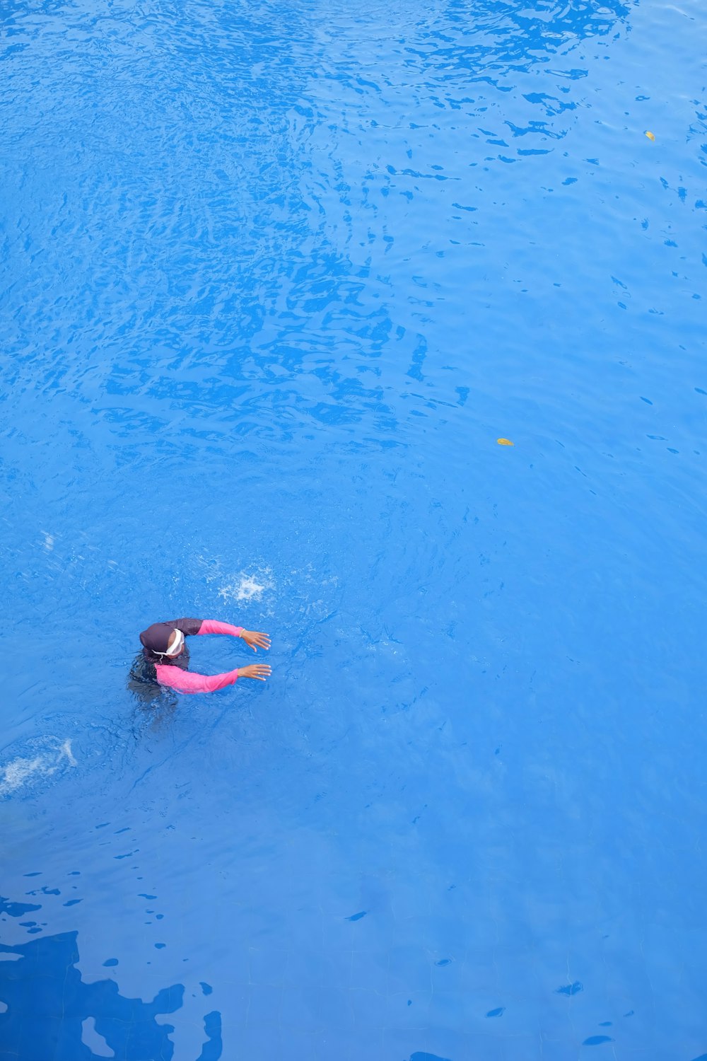 a woman swimming in a pool with a pink life jacket