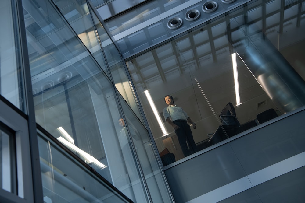 a man is standing on a glass balcony
