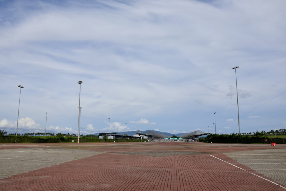 an empty parking lot with several lights and a building in the background