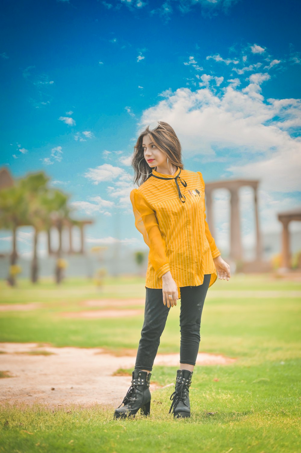 a woman standing in the grass wearing black boots