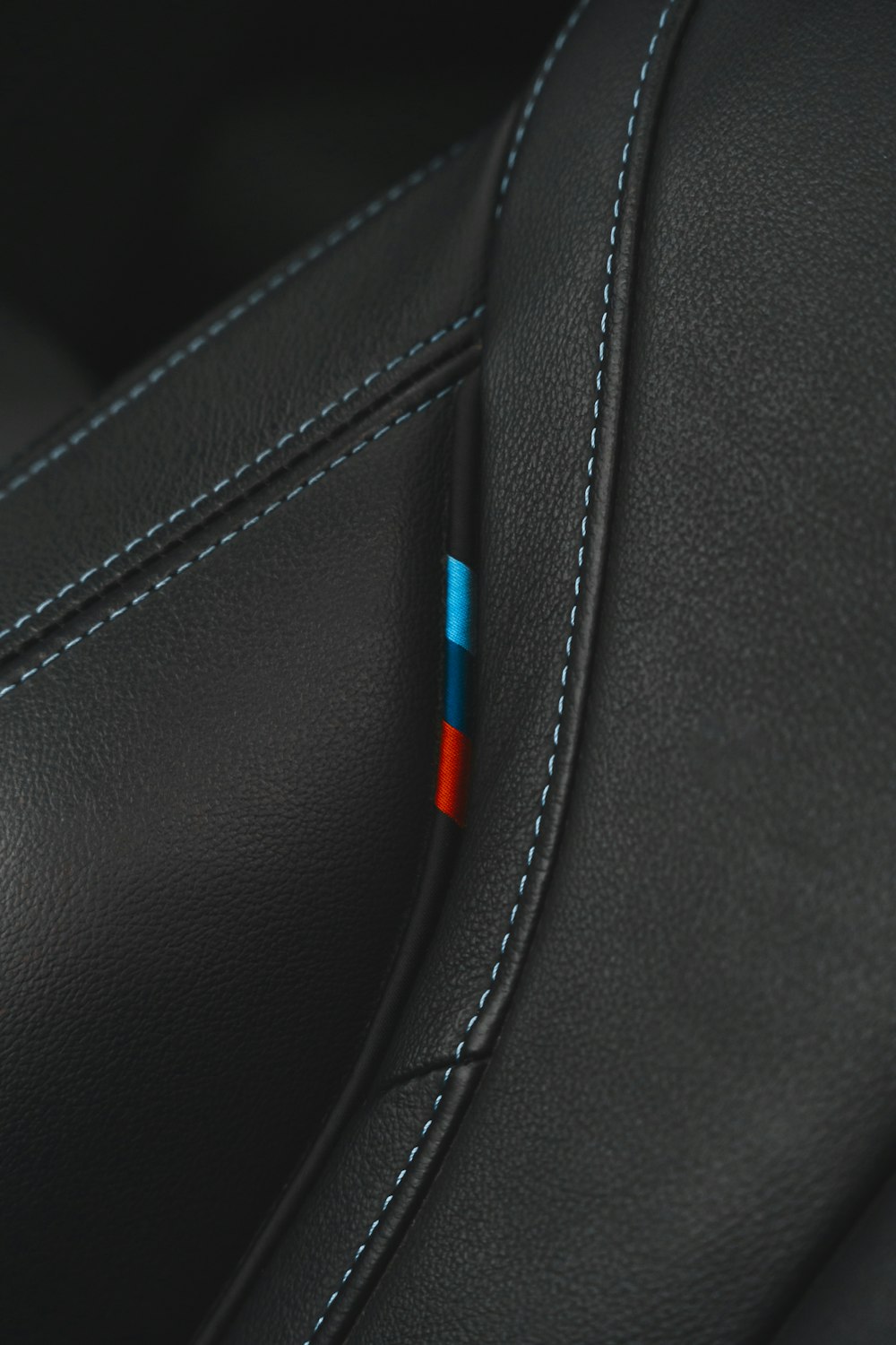 赤と青のステッチが入った黒い革張りのシートのクローズアップ