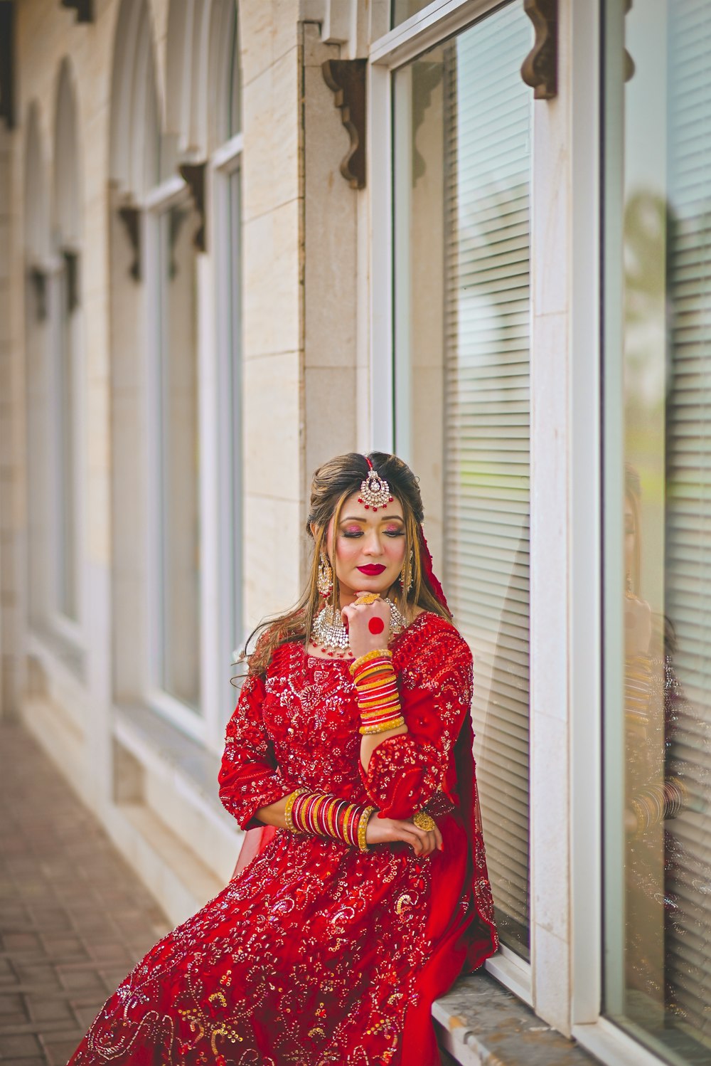 a woman in a red dress sitting on a window sill