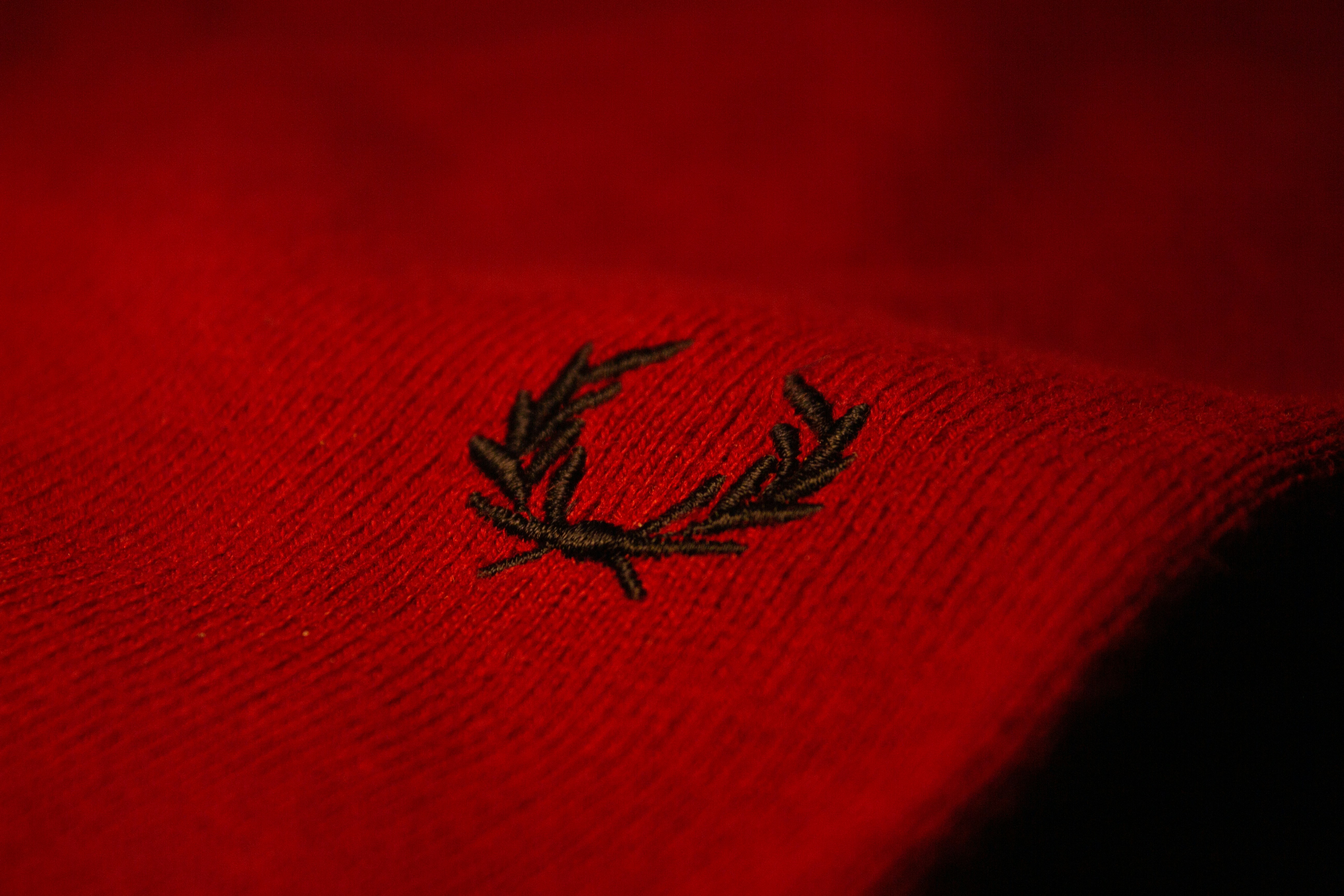 a close up of a red sweater with a leaf on it
