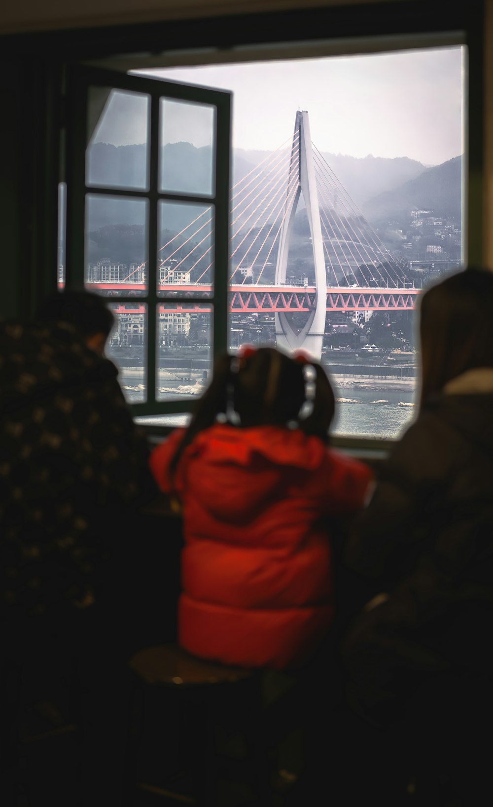 two people looking out a window at a bridge
