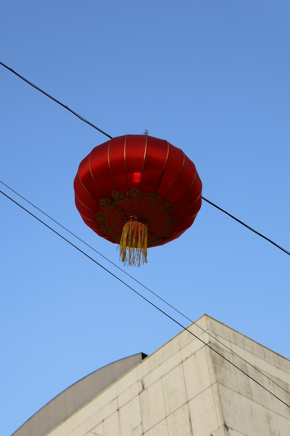 a red lantern hanging from a wire in front of a building