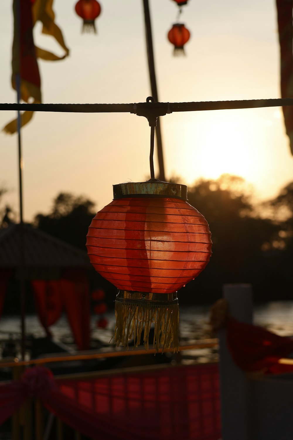 a red lantern hanging from a wire over a body of water