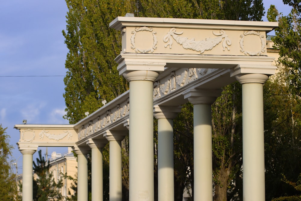 a row of white pillars sitting next to a lush green forest