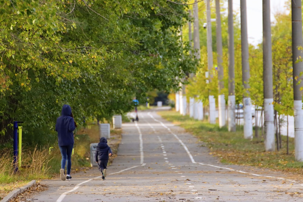 eine Person, die eine von Bäumen gesäumte Straße entlanggeht