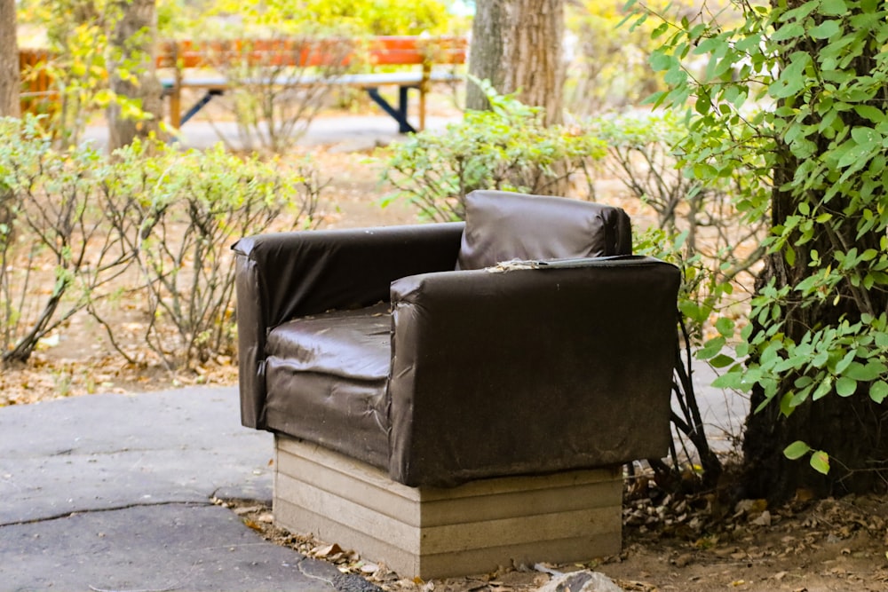 uma cadeira de couro preta sentada no meio de um parque