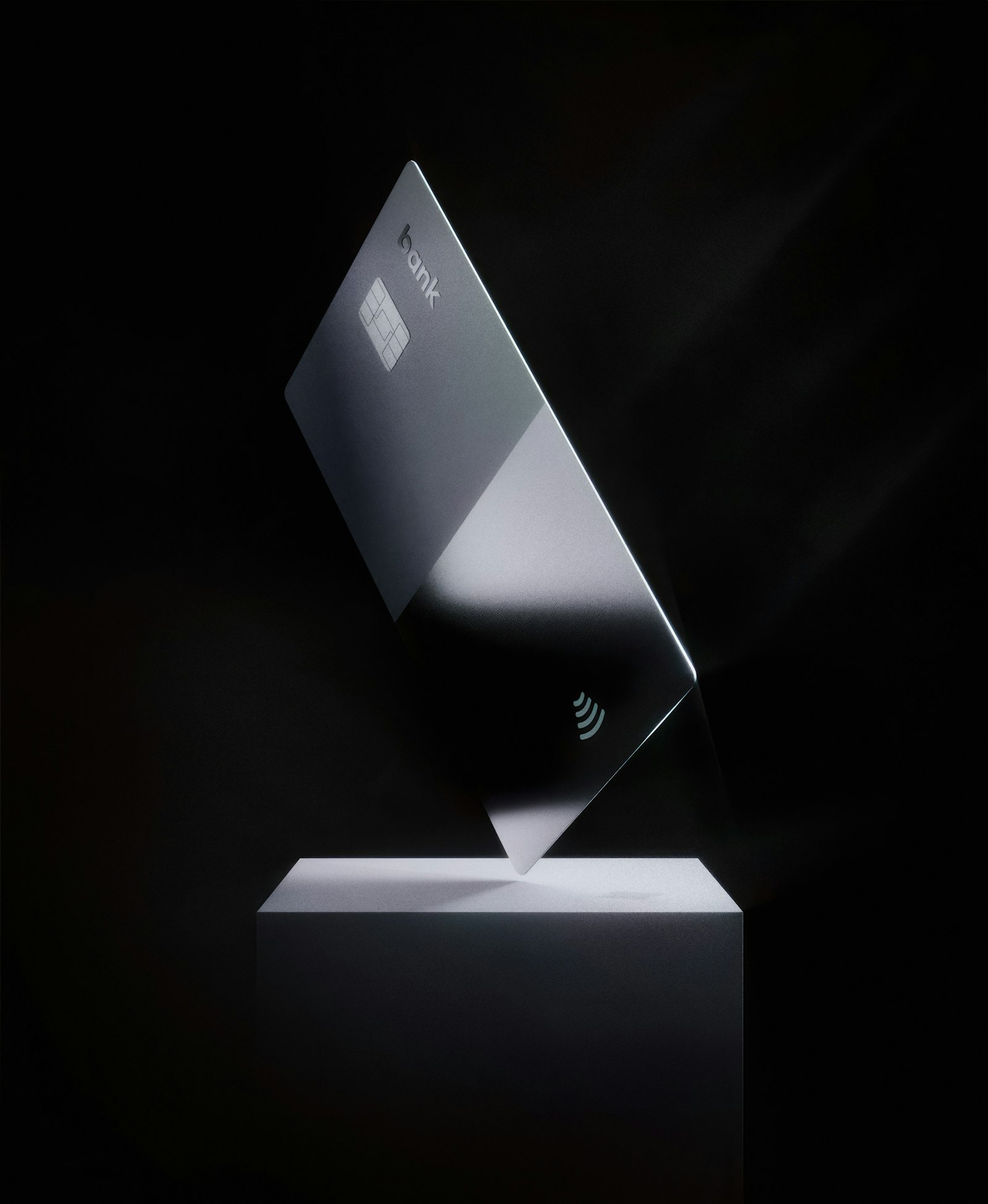 Dramatic silver premium metal credit card with EMV chip and contactless icon angled on a white pedestal against a dark backdrop — the visual stand-in for the Chase Sapphire Reserve 150K welcome offer