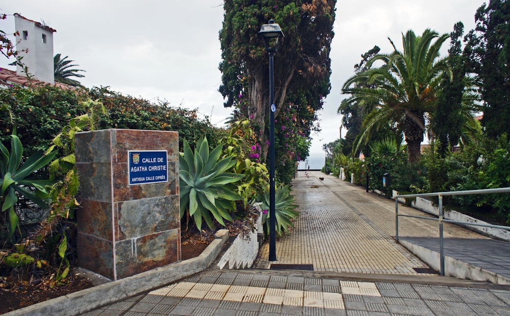 a sidewalk with a sign and some plants