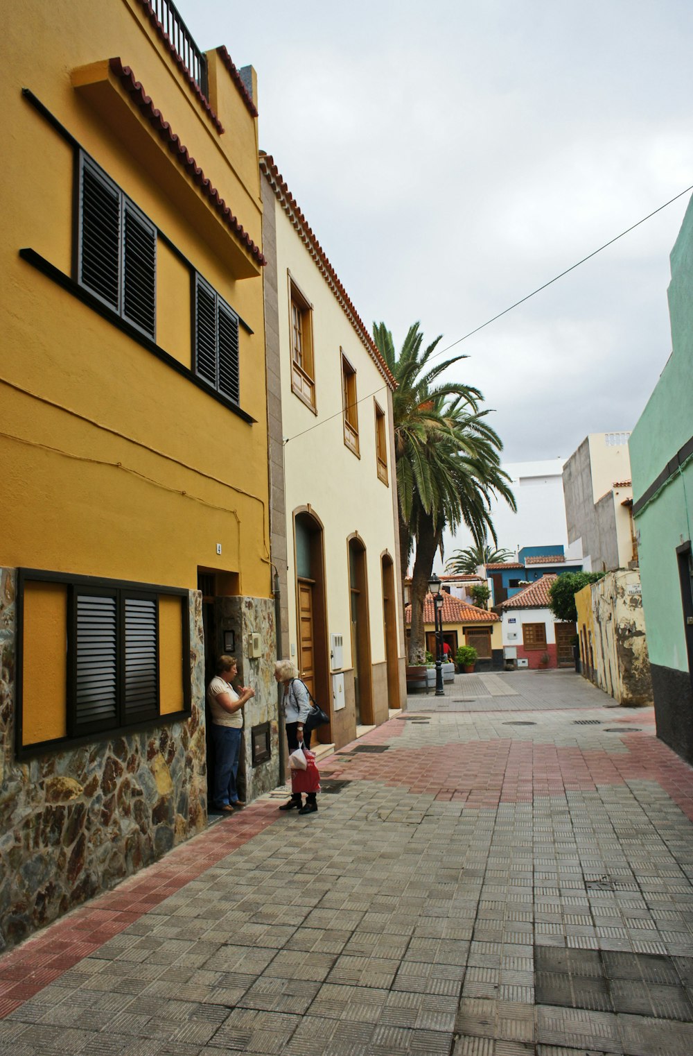 two people standing outside of a yellow building