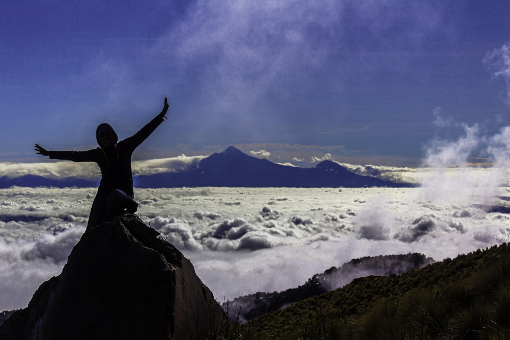 a person standing on top of a mountain above the clouds