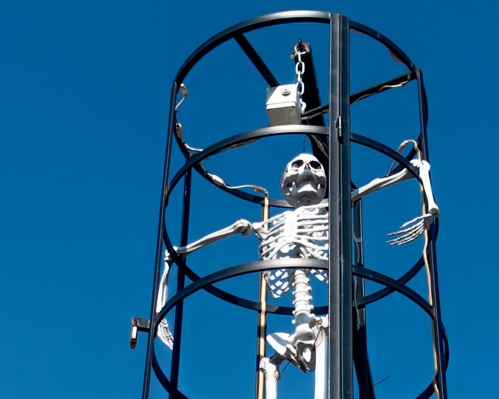 a tall metal clock tower with a skeleton on it's side