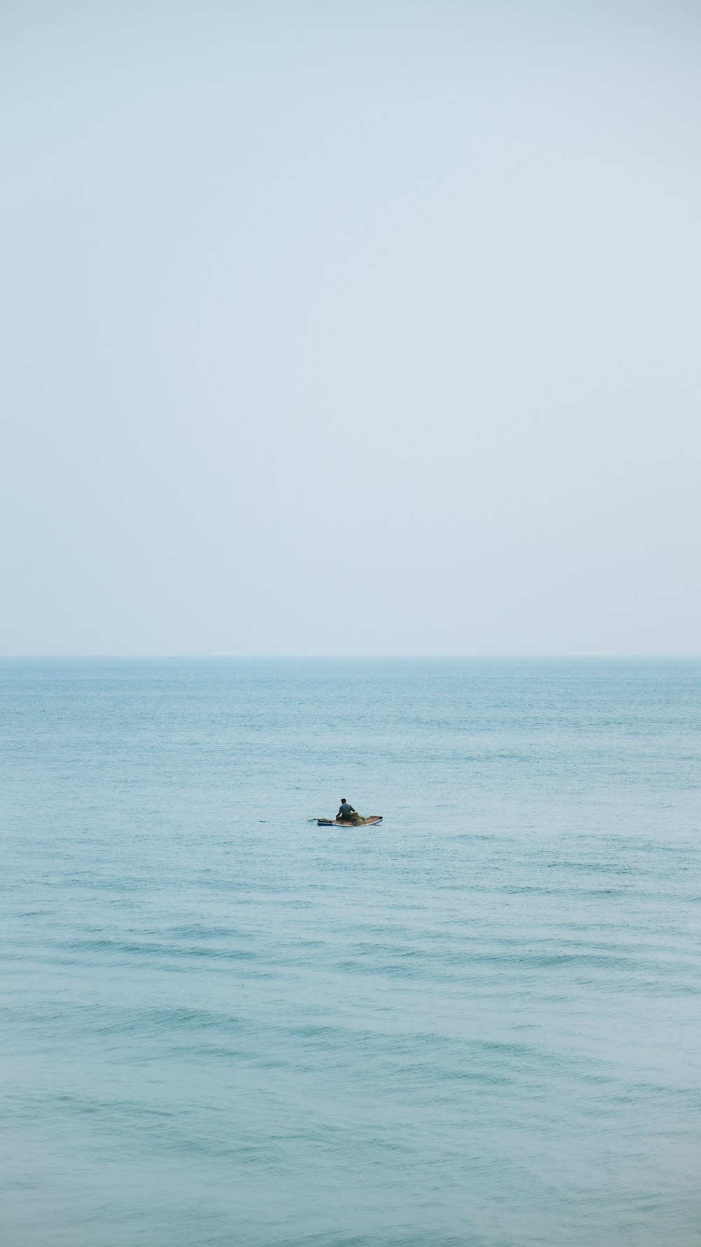 a lone boat floating in the middle of the ocean